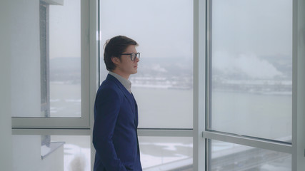 Poster - Architect wearing eyeglasses looking through the window on the urban landscape. Thinking about future construction