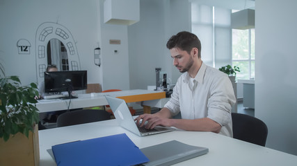Poster - Worker using computer. Businessman typing on laptop. Young mixed race employee concentrated at the work.