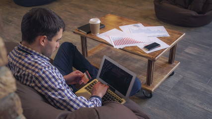 Aufkleber - Attractive man sitting on the couch, hands holding a laptop and a credit card, enter the data for payment. Soft panorama