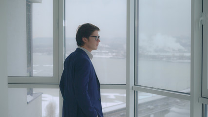 Aufkleber - portrait young caucasian businessman looking through the windows on city urban landscape with bridge river and cars on the road.
