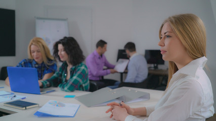 Poster - Portrait attractive woman with long fair hair in office startup company. Young businesswoman looking at the camera with friendly smile. Professional lady with natural makeup smiling. On the background