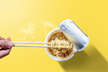 People eat the instant cup noodles with chopstick