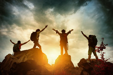 Celebrating Life Of Hikers Climbing Up Mountain Cliff. Climbing Group Helping Each Other While Climbing Up In Sunset. Concept Of Help And Teamwork, Limits Of Life And Hiking Success Full.