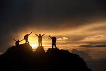 Silhouette Of Hikers Climbing Up Mountain Cliff. Climbing Group Helping Each Other While Climbing Up In Sunset. Concept Of Help And Teamwork, Limits Of Life And Hiking Success Full.