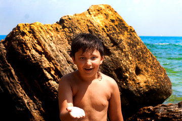 Smiling boy on the background of the sea and stones