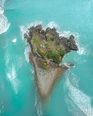 Wall Mural - Aerial view of an Island with rocks, trees and waves crashing aorund
