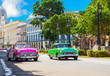 Pinker amerikanischer Cabriolet Oldtimer und grüner Oldtimer fahren auf der Hauptstrasse in Havanna Stadt Kuba - Serie Kuba Reportage