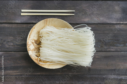 Fotomural Dried rice vermicelli on plate with chopsticks over wooden plank