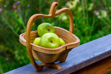Apples In A Wooden Basket In The Form Of A Large Apple On The Background Of Nature On A Wooden Railing