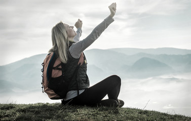 Happy woman tourist sitting on the green grass on the peak of mo