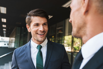 Portrait closeup of two happy businessmen partners talking together outside job center during working meeting