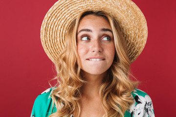 Poster - Thoughtful dreaming young beautiful blonde cute woman in dress posing isolated over red wall background looking aside.