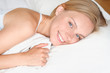 © Nastassia Yakushevic - Beautiful young blonde woman waking up and smiling in a white bed.
