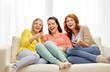 © Syda Productions - entertainment, leisure and friendship concept - three smiling teenage girls or friends with popcorn and remote watching tv at home