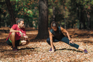 Wall Mural - Young Couple stretching after training in the park