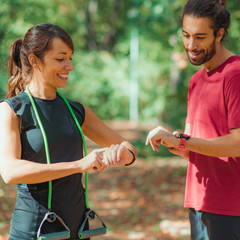 Wall Mural - Young couple Looking at Their Smart Watches After Outdoor Training