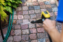 Cleaning The Garden Cobblestone Pathway With A High Pressure Washer