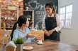 © PR Image Factory - Upset young businesswoman complain about cup of hot coffee. woman customer hold it in hands and point to order while look at waitress. lady client complaining meal to waitress in cafe store.