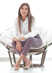 Poster - modern young young woman sitting in a comfortable chair