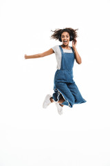 Wall Mural - Image of happy african american woman rejoicing and jumping while listening to music with headphones