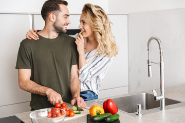 Poster - Happy couple cooking together while standing at the kitchen