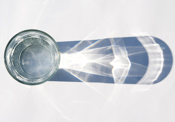 Water glass with strong shadows on white background