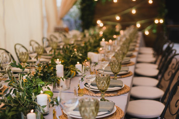 Canvas Print - Coziness and style. Modern event design. Table setting at wedding reception. Floral compositions with beautiful flowers and greenery, candles, laying and plates on decorated table.
