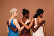 © Artem Varnitsin - Three diverse women standing against brown background hugging each other
