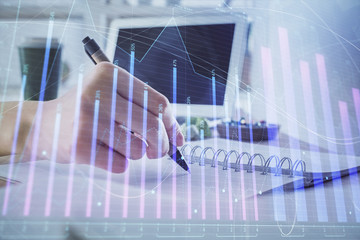 Financial forex graph drawn over hands taking notes background. Concept of research. Multi exposure