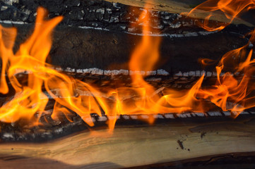 Wooden burning hot charred planks of wood logs in a fire with tongues of fire and smoke. Texture, background