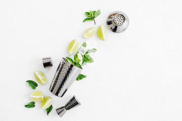 Set of bar accessories for cocktail making. Shaker, jigger, glass, spoon  and  other bar tools with lime and mint leaves on withe  background.