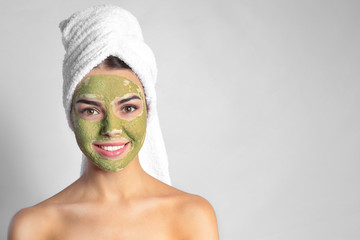 Canvas Print - Young woman with clay mask on her face against light background, space for text. Skin care