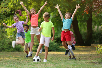 Sticker - Cute little children playing with soccer ball in park