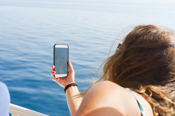 Wall Mural - Young woman taking self portrait pictures while sailing on the ship on the sea summer holiday vacation