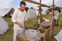 Blacksmith Heats Metal In A Medieval Horn In A Field In Summer