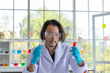 The Portrait of the Asian smart man scientist is holding two test tubes. In research laboratory