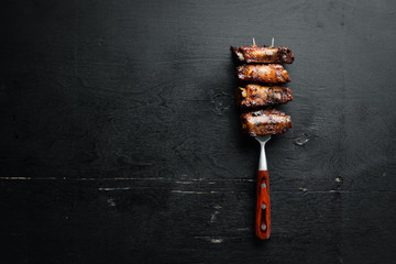 Pork ribs on the fork. On a wooden background. Top view. Free space for your text.