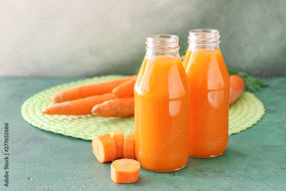 Bottles of tasty carrot juice on table