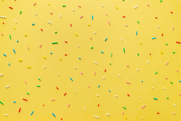 trendy pattern of colorful sprinkles over yellow background, decoration for cake and baker