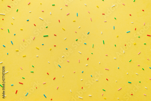 trendy pattern of colorful sprinkles over yellow background, decoration for c...