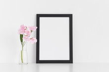 Black Frame Mockup With Pink Oleander In A Glass Vase On A White Table.Portrait Orientation.
