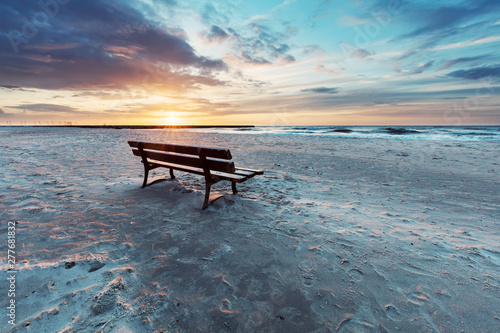 Lonely bench on the beach at sunset with view on the sea Fototapet