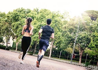 Couple of young people running wearing technical dressing in a park