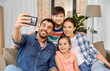 © Syda Productions - family, technology and people concept - happy father, mother, little son and daughter taking selfie by smartphone at home