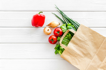 Wall Mural - Healthy food with fresh vegetables in paper bag on white wooden background top view space for text