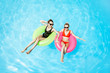© rh2010 - Two women swimming on the inflatable rings, relaxing in the water pool outdoors during the summer time, View from above