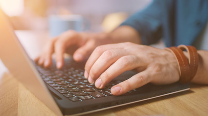 Wall Mural - Close-up Shot of a Man Typing on a Laptop at Home / Office. Shot Made with Warm Sun Light.