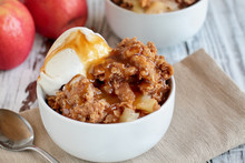 Fresh Hot Homemade Apple Crisp Or Crumble With Crunchy Streusel Topping Topped With Vanilla Bean Ice Cream And Caramel Sauce. Selective Focus With Blurred Background