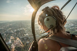 Portrait of beautiful blonde women enjoying helicopter flight. She is amazed by cityscape.
