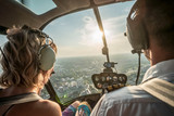 Portrait of beautiful blonde women and pilot enjoying helicopter flight. She is amazed by cityscape.